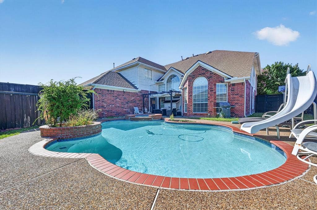 1625 Falmouth Drive, Plano, TX 75025 Backyard oasis featuring a curvilinear swimming pool with brick coping, an integrated spa, and an exposed aggregate concrete deck