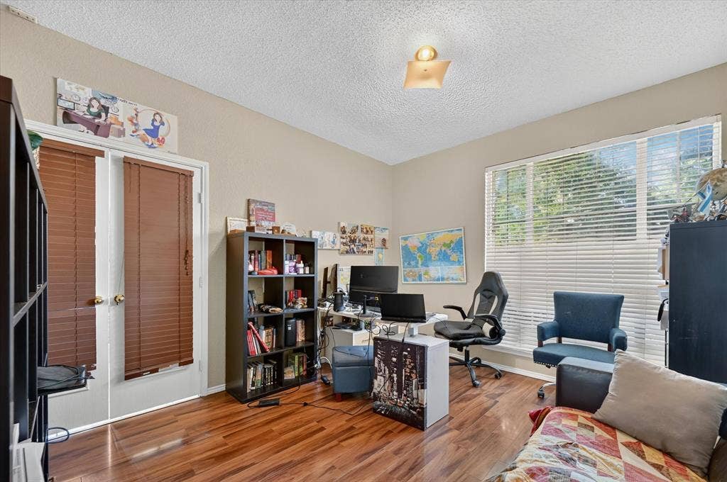 1625 Falmouth Drive, Plano, TX 75025 Spacious room featuring wood-finish flooring, ample natural light from a large window, and double doors with privacy blinds