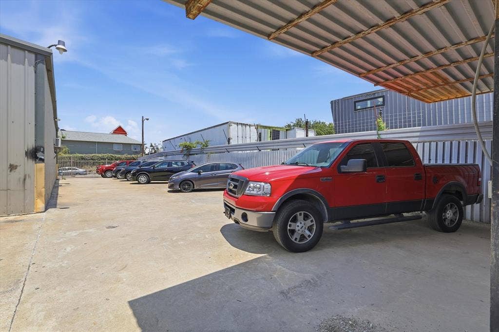 2136 California Crossing Road, Dallas, TX 75220 Concrete lot with covered parking structure featuring corrugated metal roofing and a corrugated metal fence