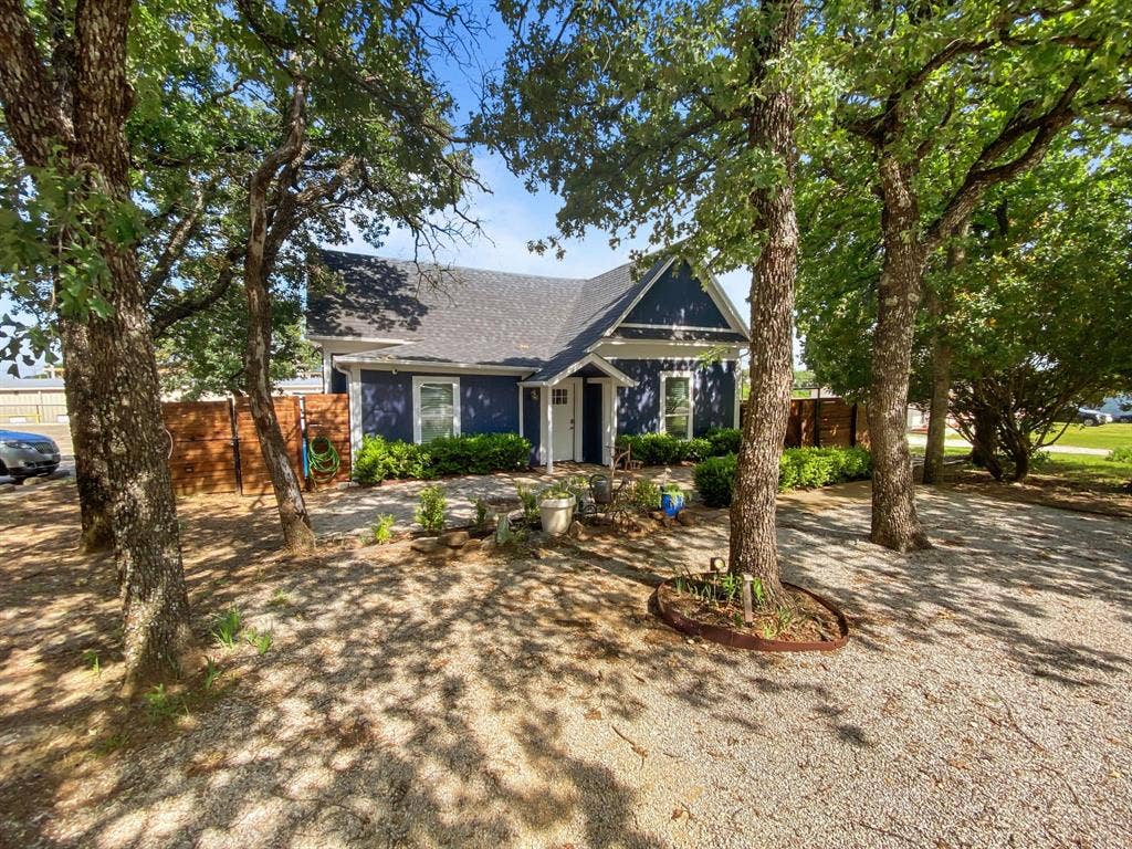 815 Stonecrest Road, Argyle, TX 76226 Dark blue siding exterior with white trim, a gabled roof, and a gravel front parking