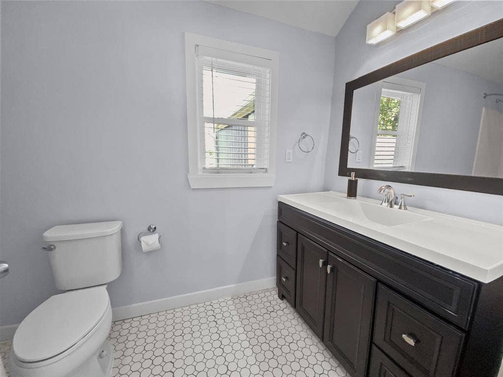 815 Stonecrest Road, Argyle, TX 76226 Hexagonal tile flooring, dark wood-finish vanity with white countertop, chrome faucet, and a large framed mirror
