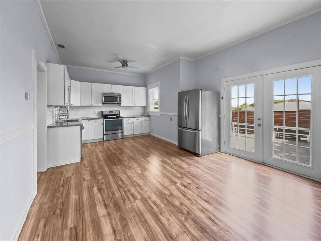 815 Stonecrest Road, Argyle, TX 76226 Kitchen featuring wood-finish flooring, white cabinetry, stainless steel appliances, and a subway tile backsplash