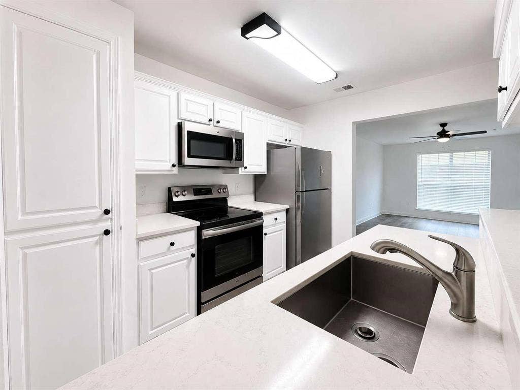 305 N Arizona Drive, #307, Celina, TX 75009 Kitchen featuring white cabinetry, stainless steel appliances, light-toned countertops, an undermount sink with a gooseneck faucet, and hard-surface flooring