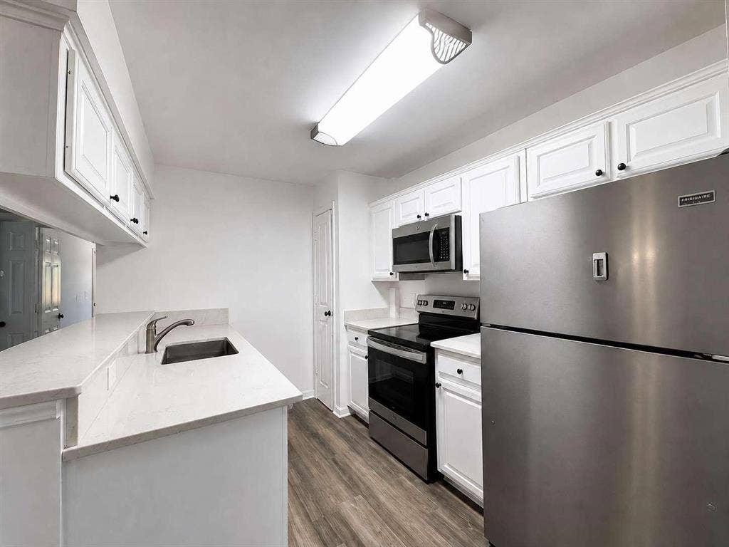 305 N Arizona Drive, #307, Celina, TX 75009 Kitchen featuring white cabinetry, light-colored countertops, stainless steel appliances, and wood-finish flooring