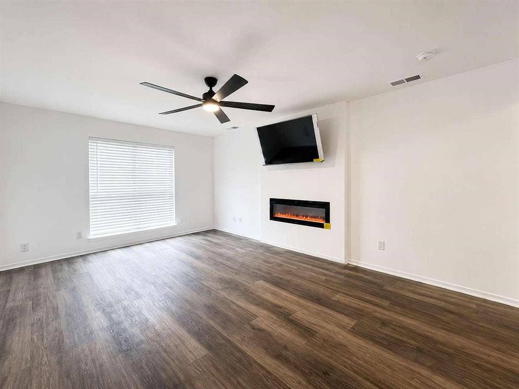 305 N Arizona Drive, #307, Celina, TX 75009 Spacious room featuring wood-finish flooring, a contemporary ceiling fan, and an integrated linear electric fireplace