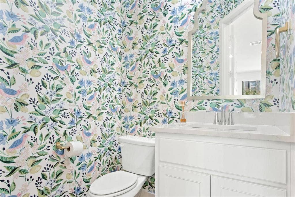 7867 Verona Place, Dallas, TX 75231 Powder room featuring botanical and bird-patterned wallpaper, white vanity with paneled cabinetry, integrated sink, and chrome faucet