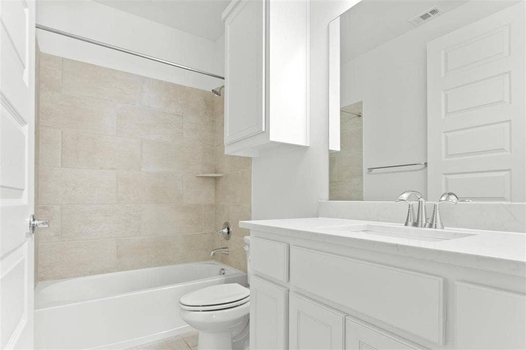 7867 Verona Place, Dallas, TX 75231 Bathroom featuring a white bathtub, light-toned tile surround with integrated shelf, and chrome fixtures