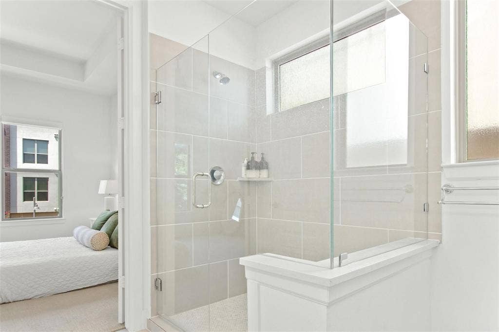 7867 Verona Place, Dallas, TX 75231 Frameless glass shower enclosure featuring large format light gray wall tiles and a built-in shower niche