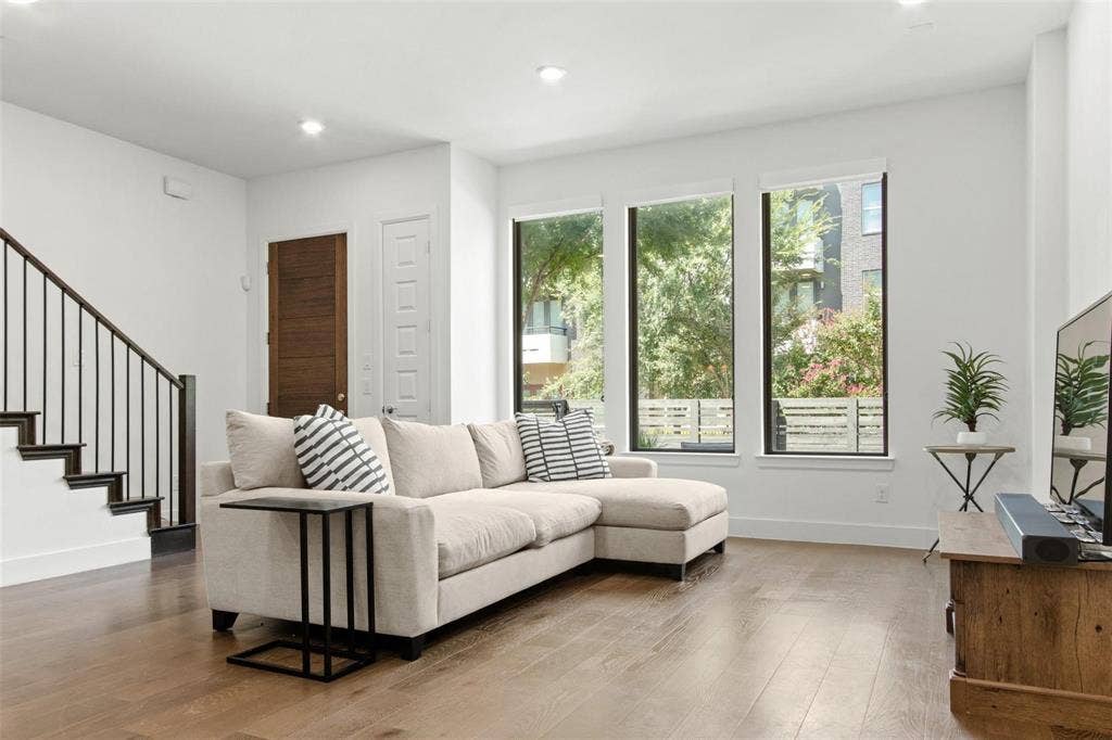 7867 Verona Place, Dallas, TX 75231 Living area featuring three large windows, recessed lighting, wood-finish flooring, and a dark wood staircase with black metal balusters