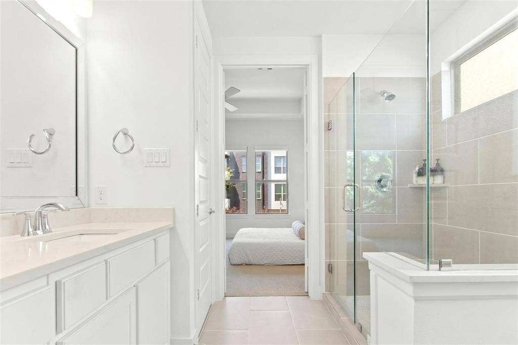 7867 Verona Place, Dallas, TX 75231 Bathroom featuring a glass-enclosed shower with large format tile surround, a built-in shower niche, and a fixed showerhead
