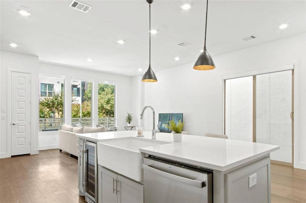 7867 Verona Place, Dallas, TX 75231 Kitchen island with a white farmhouse sink, stainless steel dishwasher, and built-in beverage cooler