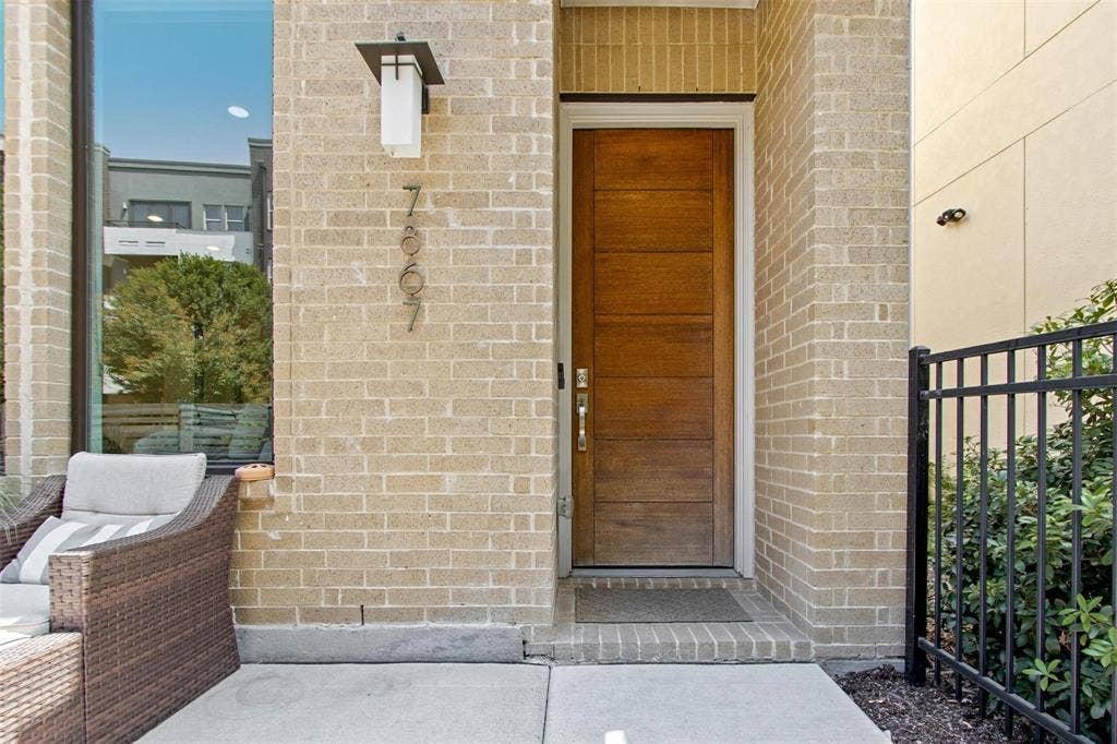 7867 Verona Place, Dallas, TX 75231 Contemporary wood-finish entry door with horizontal paneling, complemented by a modern exterior sconce