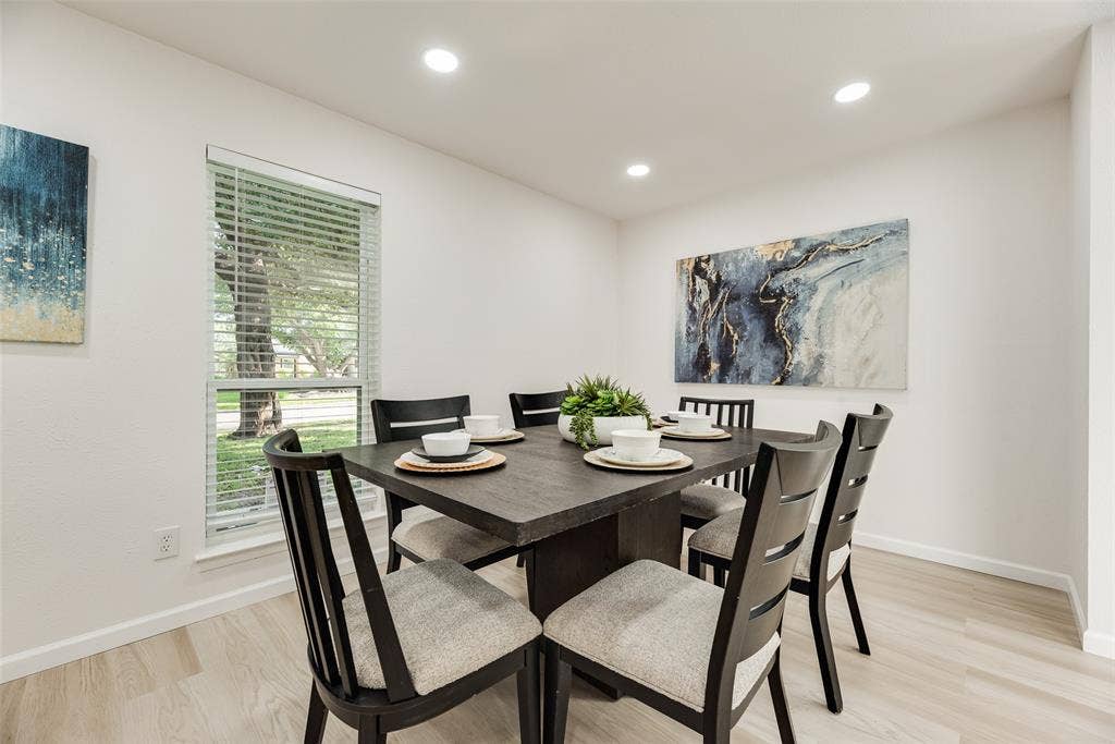 Recessed lighting illuminates this dining space featuring wood-finish flooring, white baseboards, and a window with blinds
