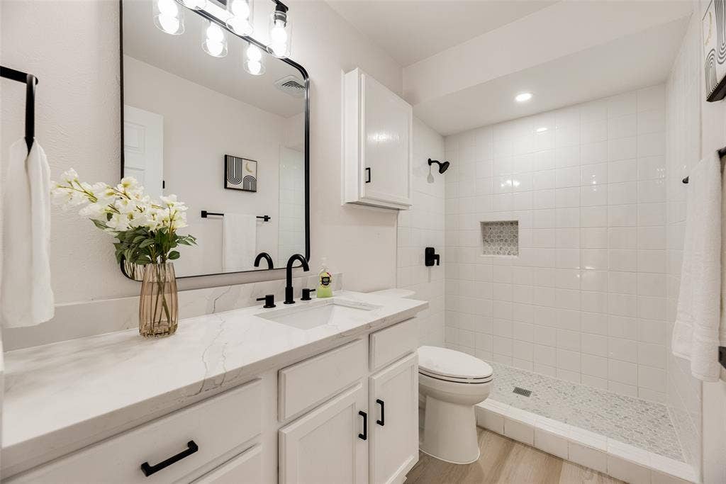 Bathroom featuring a single vanity with stone-finish countertop, undermount sink, and matte black fixtures