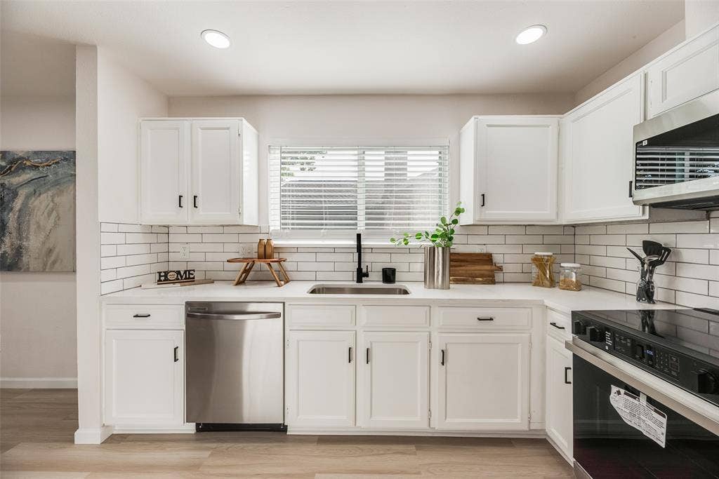 Kitchen featuring white cabinetry, subway tile backsplash, stainless steel dishwasher, and a built-in oven with microwave