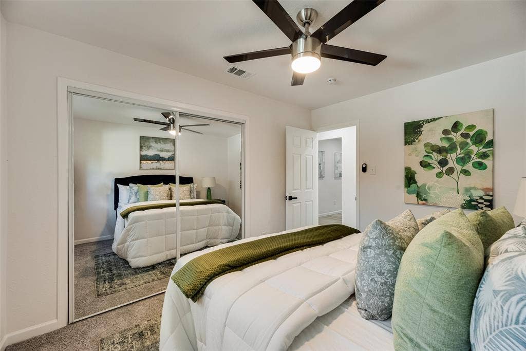 Bedroom featuring a ceiling fan with light, mirrored closet doors, and carpeted flooring