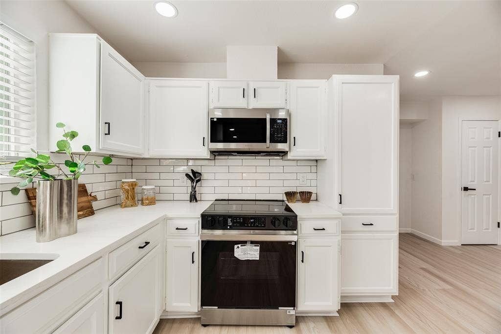 Kitchen featuring crisp white cabinetry, stainless steel appliances, white subway tile backsplash, recessed lighting, and light wood-finish flooring