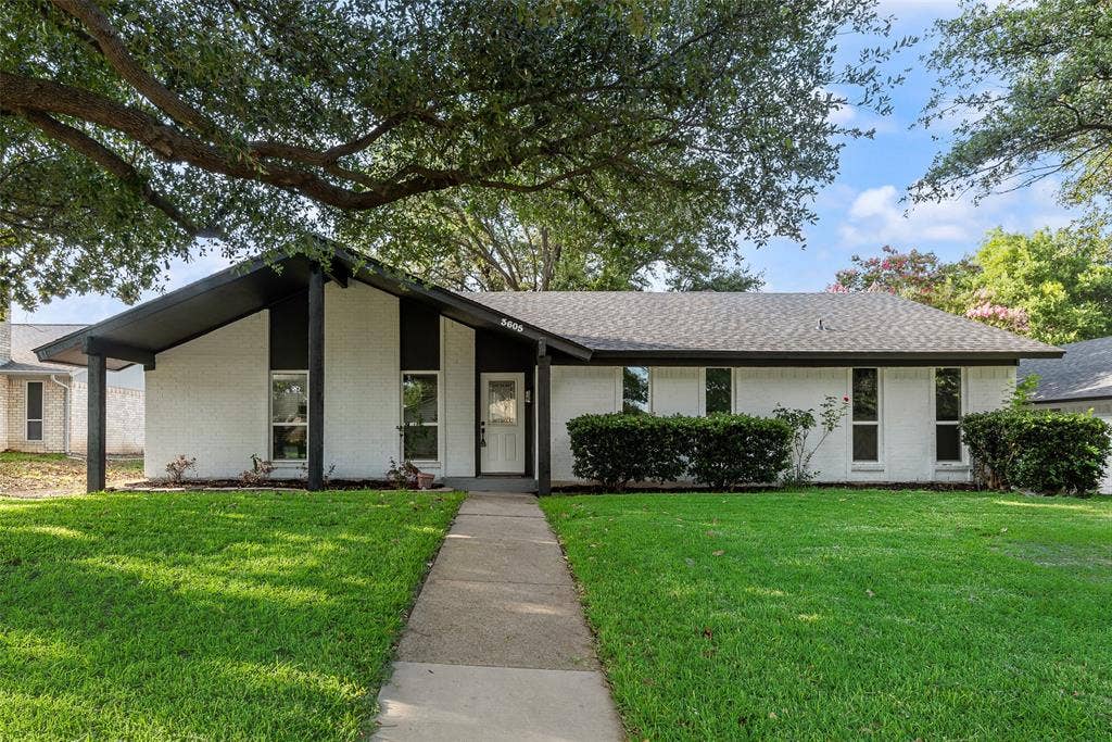 Single-story residence featuring a white brick facade with black trim accents and a dark-shingled roof