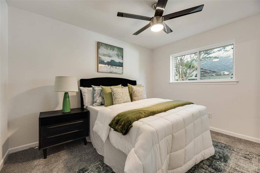 Bedroom featuring light grey carpeting, white walls, a single-pane window, and a ceiling fan with integrated lighting