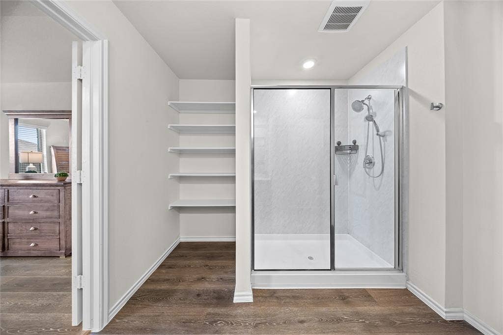 2920 Roper Street, Royse City, TX 75189 Modern shower enclosure with a glass door, white shower base, and integrated shelving