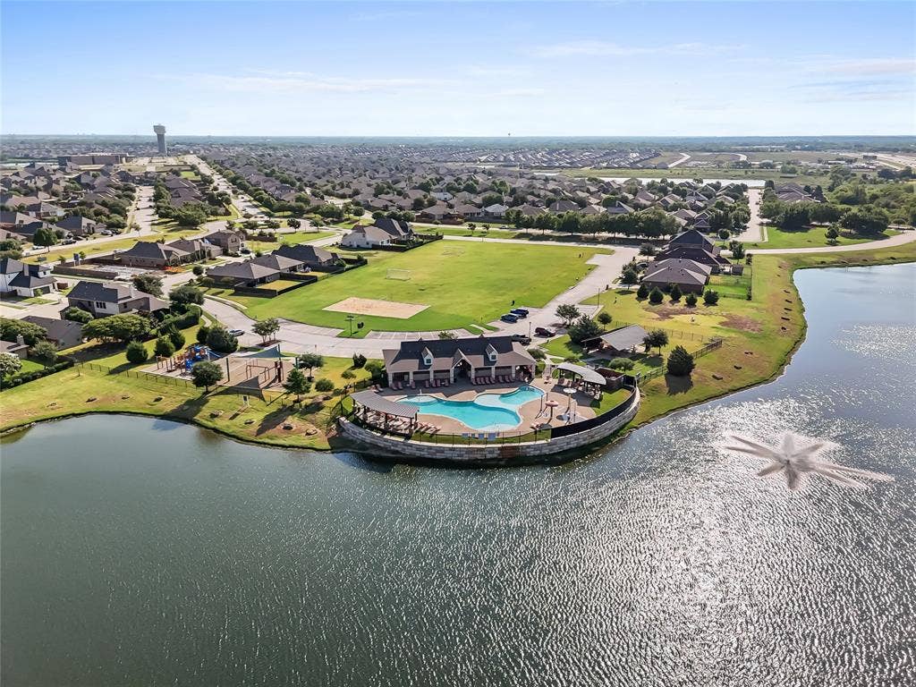 2920 Roper Street, Royse City, TX 75189 Community lakefront amenity center featuring a swimming pool with integrated spa, a shaded outdoor lounge area, and an adjacent playground