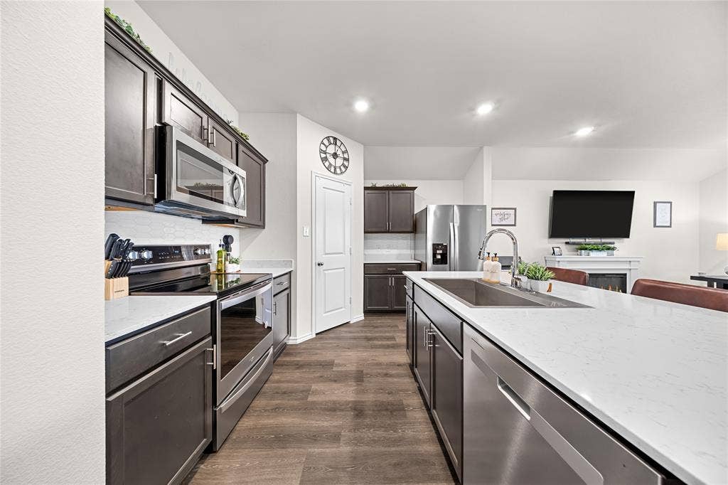 2920 Roper Street, Royse City, TX 75189 Chef's kitchen featuring stainless steel appliances, including dual wall ovens and a built-in microwave, paired with sleek black cabinetry and white quartz countertops