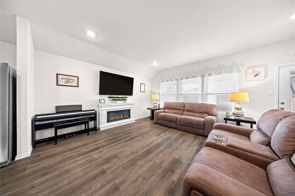 2920 Roper Street, Royse City, TX 75189 Spacious interior featuring wood-finish flooring, a contemporary fireplace with a white mantel, and multiple windows providing natural light