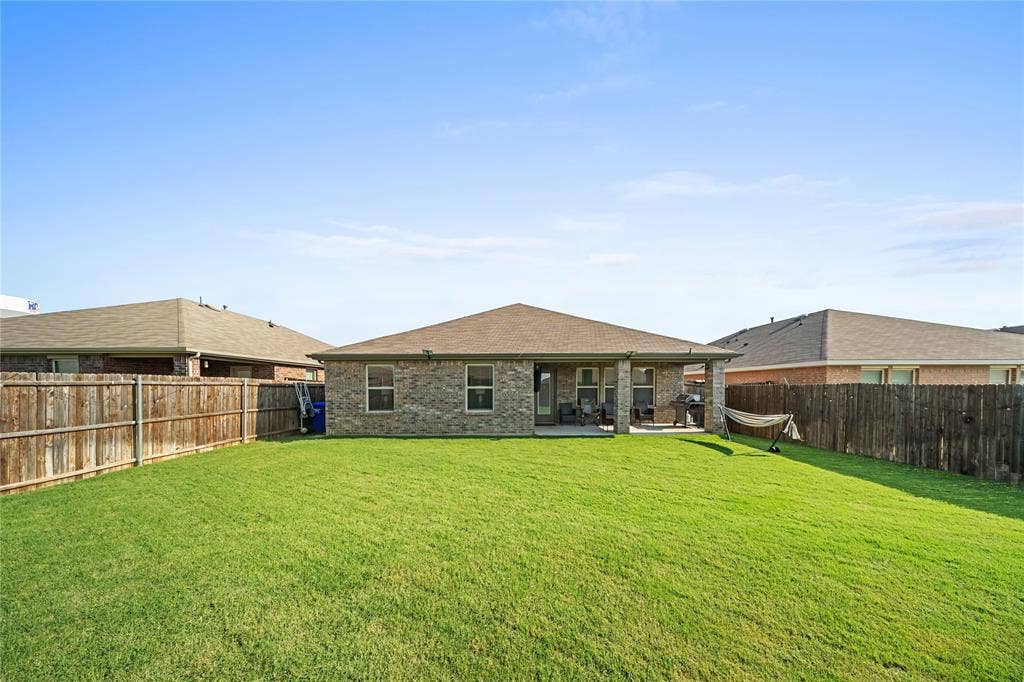 2920 Roper Street, Royse City, TX 75189 Expansive backyard featuring a manicured lawn, full privacy fencing, and a covered concrete patio