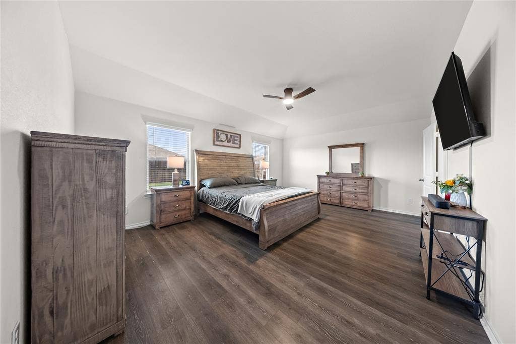 2920 Roper Street, Royse City, TX 75189 Spacious room featuring wood-finish flooring, two windows with blinds, a ceiling fan, and white walls