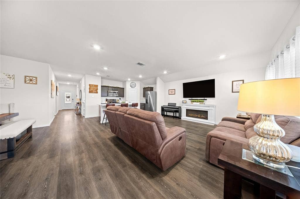 2920 Roper Street, Royse City, TX 75189 Open-concept living area featuring wood-finish flooring, recessed lighting, and a modern electric fireplace with a white mantel