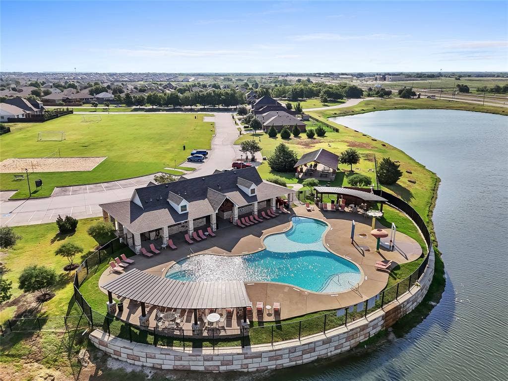 2920 Roper Street, Royse City, TX 75189 Community clubhouse with a large swimming pool, surrounded by a lake, expansive green space, and a sand volleyball court