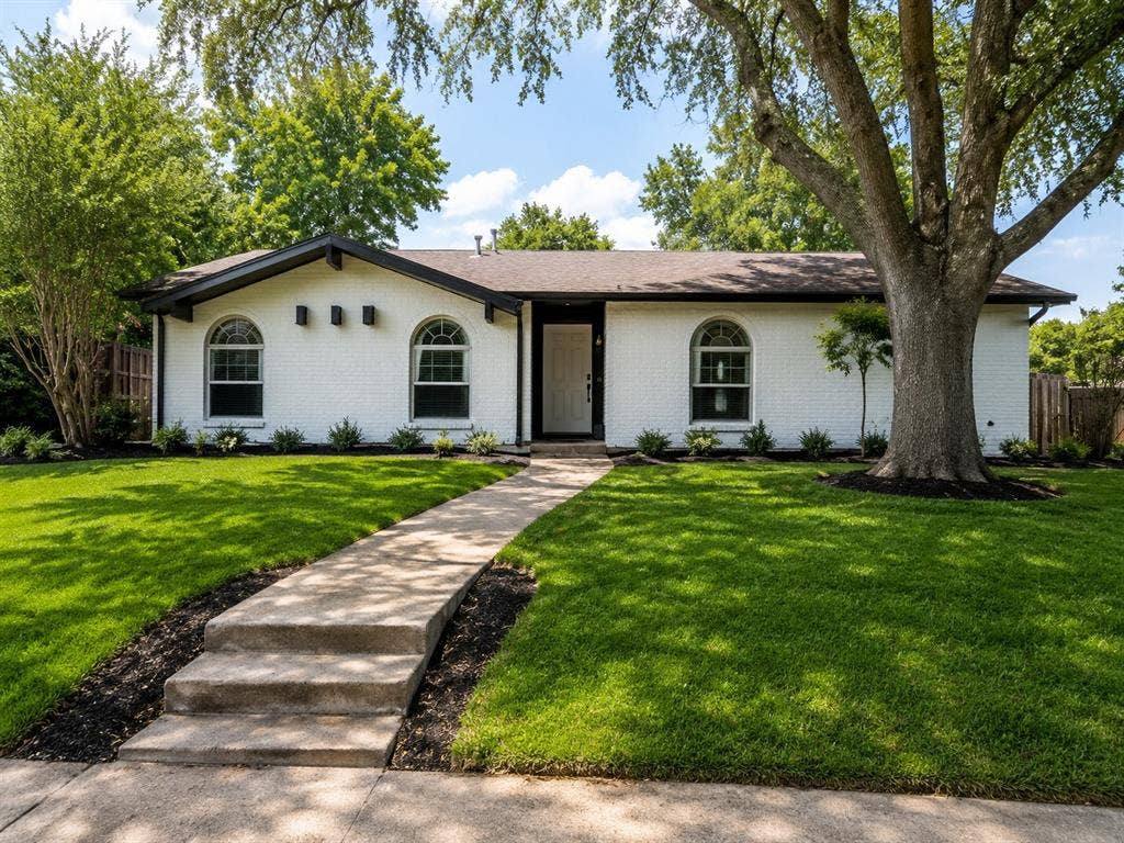 Charming single-story residence featuring a crisp white exterior with arched windows and a covered entry