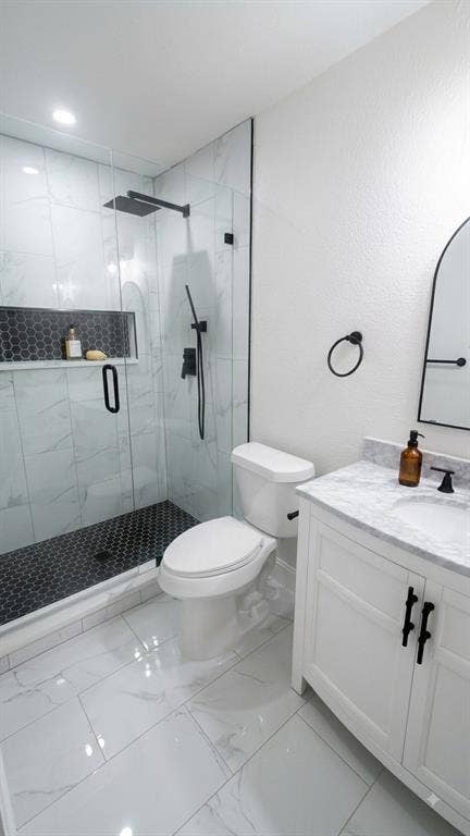 Glass-enclosed shower with matte black fixtures and a hexagonal tile floor