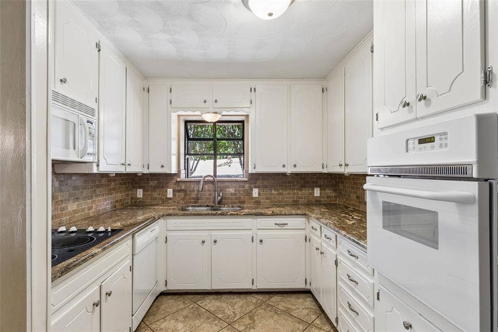 505 Caduceus Lane, Hurst, TX 76053 Built in microwave, cooktop and bright white stove are offset by the warm colors in the newer tile floors, granite and backsplash.