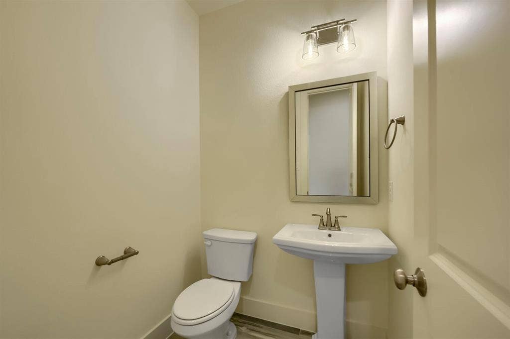 690 Red Cedar Road, Haslet, TX 76052 Pedestal sink with chrome faucet, wall-mounted mirror, and overhead vanity lighting