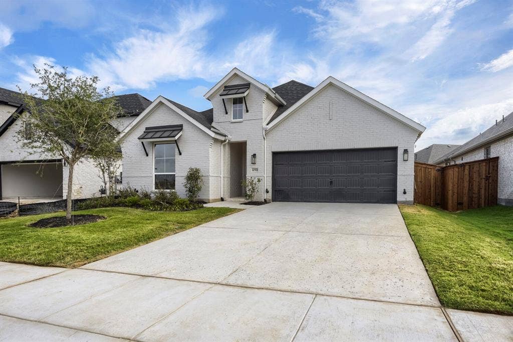 690 Red Cedar Road, Haslet, TX 76052 White brick exterior with dark trim accents, a two-car garage, concrete driveway, and established landscaping