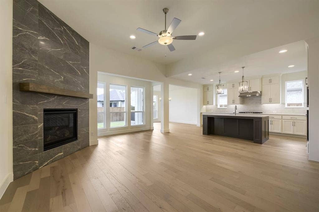 690 Red Cedar Road, Haslet, TX 76052 Spacious interior featuring wood-finish flooring, a contemporary fireplace with a wood mantle, and a kitchen island with pendant lighting