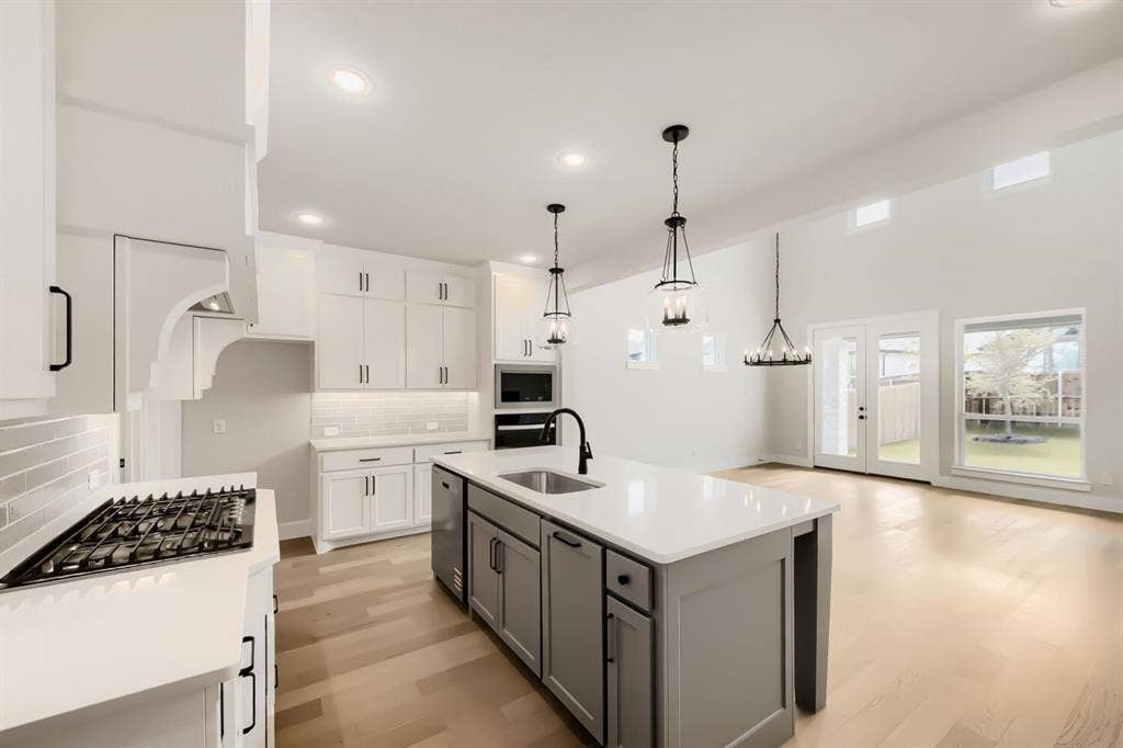 1281 White Pine Drive, Haslet, TX 76052 Spacious kitchen featuring white cabinetry, a large center island with a sink, stainless steel appliances, and wood-finish flooring