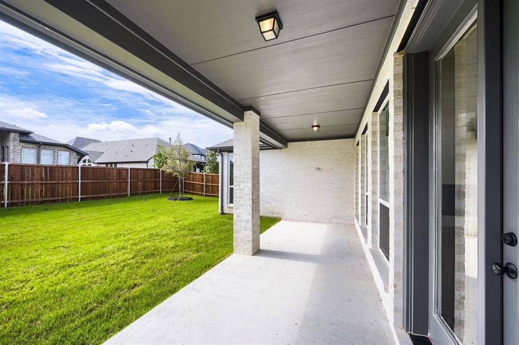 1281 White Pine Drive, Haslet, TX 76052 Covered concrete patio with white brick exterior, multiple windows, and a green lawn