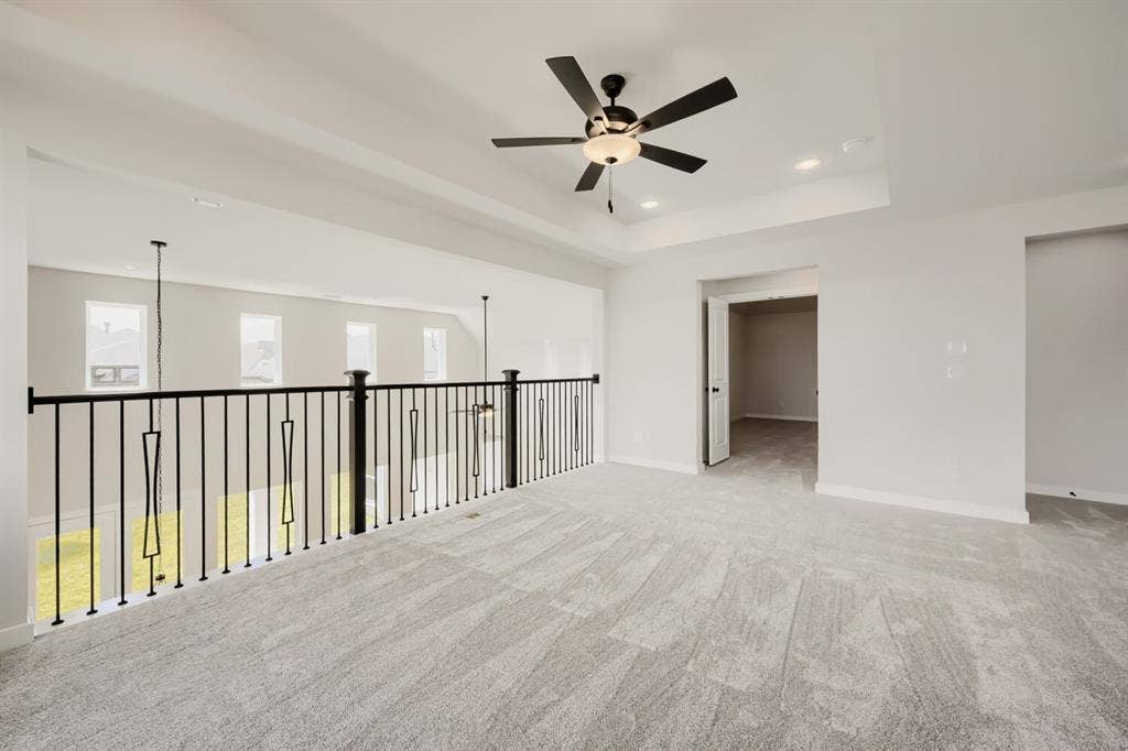 1281 White Pine Drive, Haslet, TX 76052 Expansive open-concept room featuring light-toned carpet, a contemporary black metal baluster railing, and a tray ceiling with recessed lighting