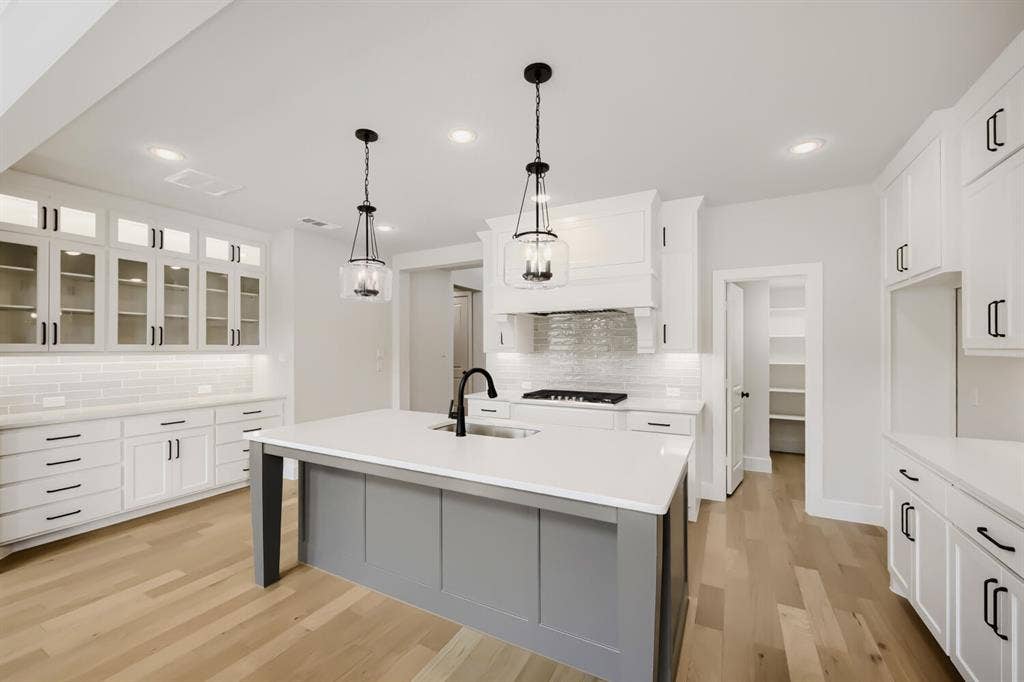 1281 White Pine Drive, Haslet, TX 76052 Kitchen featuring a central island with a sink, white cabinetry with dark hardware, wood-finish flooring, recessed lighting, and a pantry with built-in shelving