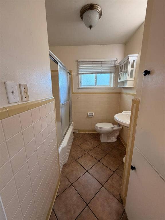 5106 Reiger Avenue, Dallas, TX 75214 Bathroom featuring tile flooring, a tub-shower combination with a sliding glass door, a wall-mounted medicine cabinet, and a pedestal sink