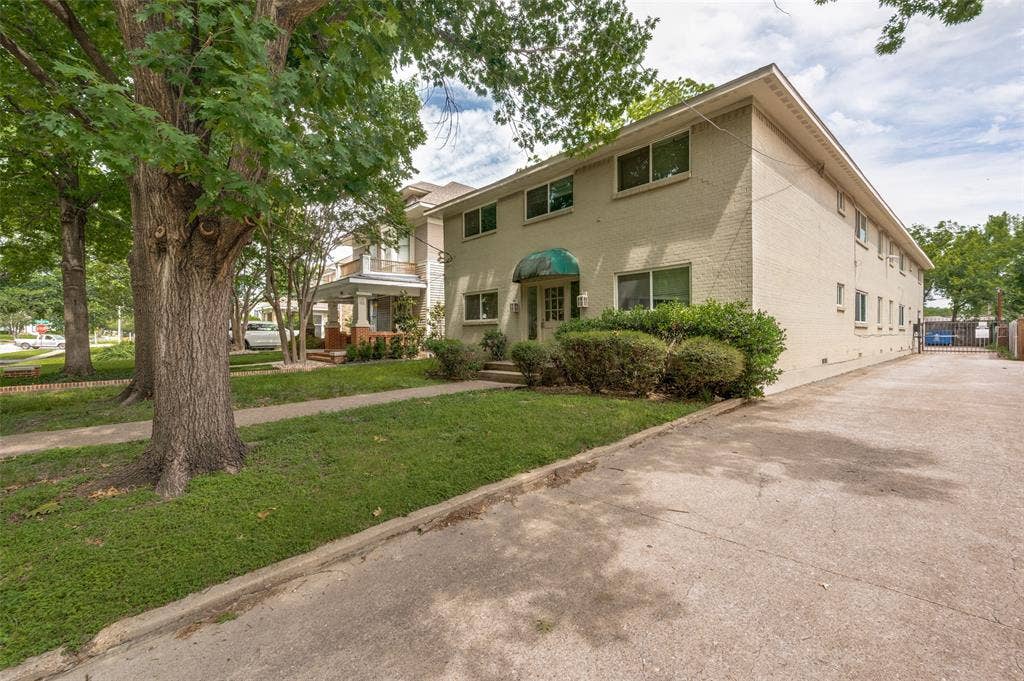 5106 Reiger Avenue, Dallas, TX 75214 Charming brick residence featuring a welcoming front façade with multi-pane windows, a covered entry portico, and mature landscaping