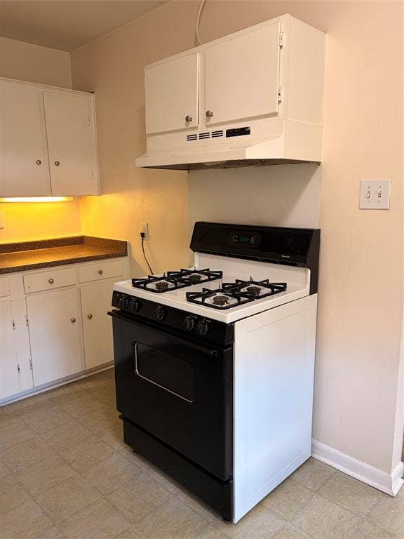 5106 Reiger Avenue, Dallas, TX 75214 White cabinetry, solid-surface countertops, and a black-and-white gas range with an integrated hood