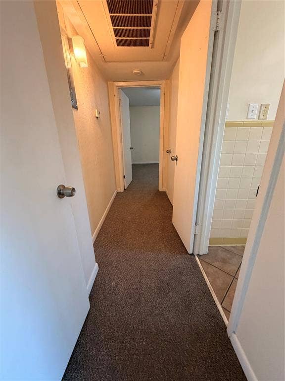 5106 Reiger Avenue, Dallas, TX 75214 Hallway featuring neutral carpeting, wall-mounted light fixtures, and solid-core interior doors with metallic hardware