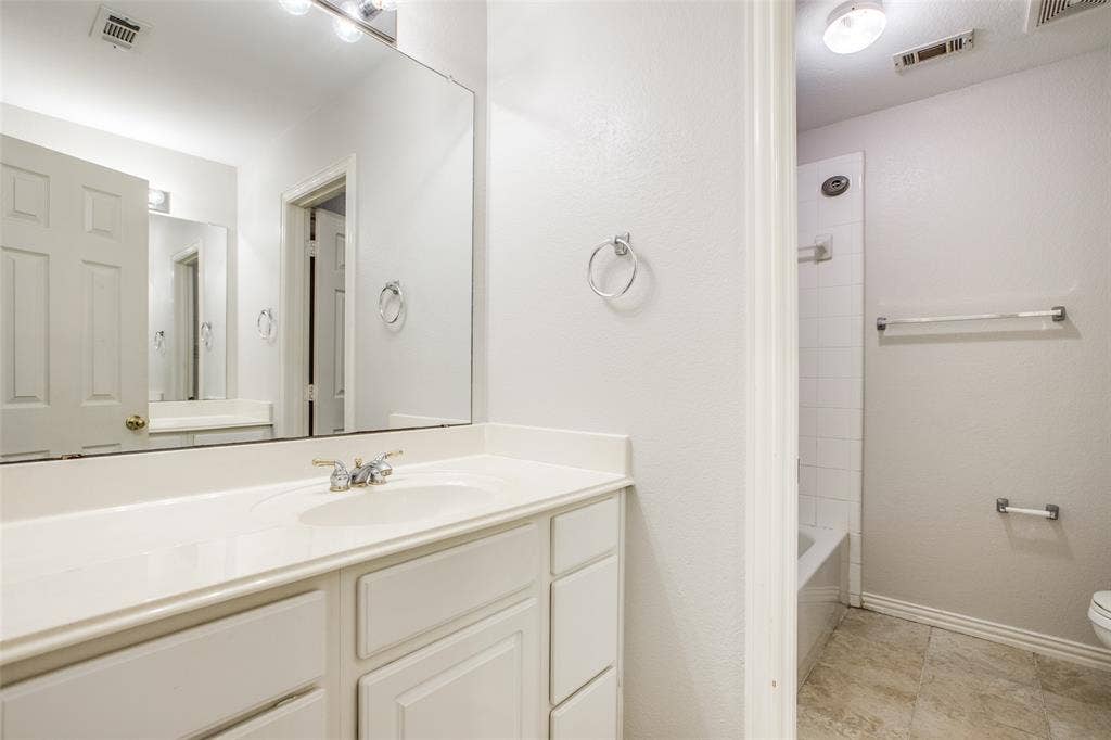 3401 Maddock Drive, McKinney, TX 75070 Spa-inspired master bathroom featuring an expansive vanity with dual sinks, abundant storage cabinetry, and a large framed mirror with integrated lighting