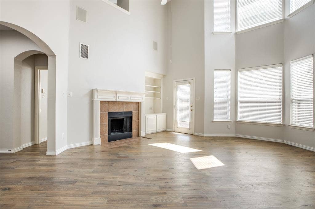 3401 Maddock Drive, McKinney, TX 75070 Spacious great room showcasing soaring ceilings with clerestory windows, wood-finish flooring throughout, and a brick fireplace with dark surround