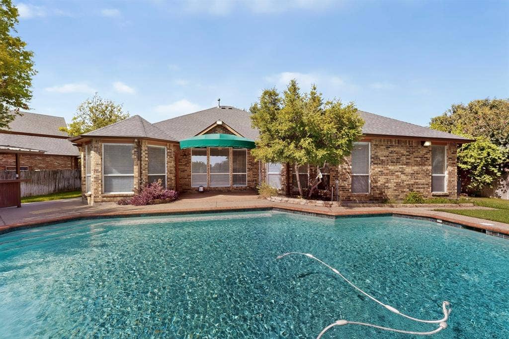 713 Mockingbird Court, Crowley, TX 76036 Expansive swimming pool with a concrete surround, brick exterior, multiple windows, and a green awning