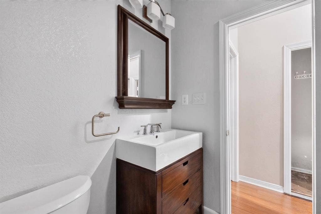 713 Mockingbird Court, Crowley, TX 76036 Wood-finish vanity with drawer storage, white rectangular vessel sink, and silver-tone fixtures