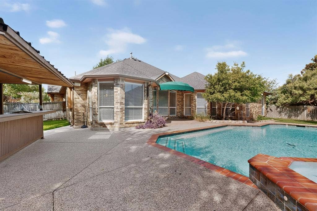 713 Mockingbird Court, Crowley, TX 76036 Pebble-finish concrete patio with a built-in bar, covered outdoor area, and a large swimming pool with a hot tub